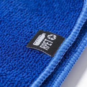 A blue towel made from recycled materials, featuring a woven label indicating its eco-friendly composition.