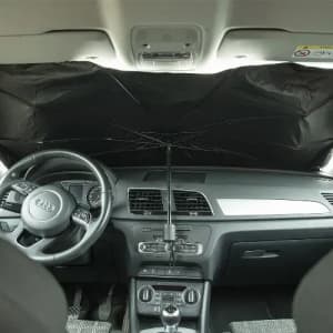 A car interior featuring a black sunshade positioned against the windscreen, with a steering wheel and dashboard visible.