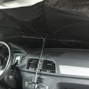 A black umbrella positioned inside a car, partially extended to provide shade or protection from sunlight.