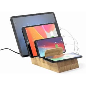 A charging station with a wooden base, holding multiple devices including a tablet and two smartphones.