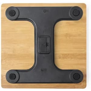 A weighing scale with a black base and a wooden surface, featuring a central locking mechanism and rubber grips.