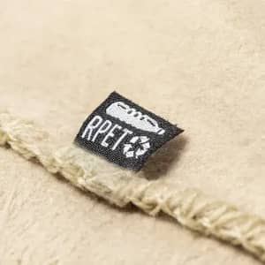A close-up of a textured, beige fabric featuring a small black label with recycling symbols and the text "RPET".