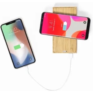 A bamboo wireless charger with two smartphones placed on it, one connected via a cable.