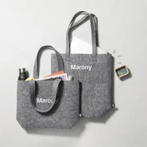 Two grey felt tote bags with handles, one larger with a document and a smaller containing a drink bottle.