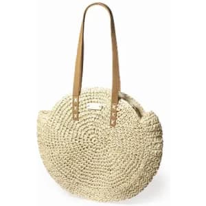 A straw tote bag with a round shape and brown leather straps, featuring a logo on the front.