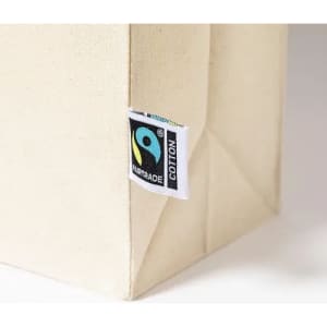 A cream-coloured cotton bag with a Fairtrade tag attached to the side.