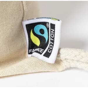 A cream-coloured fabric item with a Fairtrade Cotton tag featuring a logo, highlighting its sustainable material.