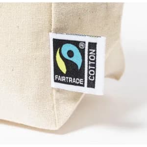 A close-up of a beige cotton bag featuring a Fairtrade logo patch.