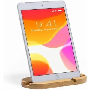 A tablet on a wooden stand, displaying a colourful screen with shades of orange and pink. The stand has a natural wooden finish.
