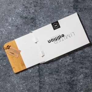 A promotional product brochure with a bamboo cover and a tag, resting on a textured grey surface.