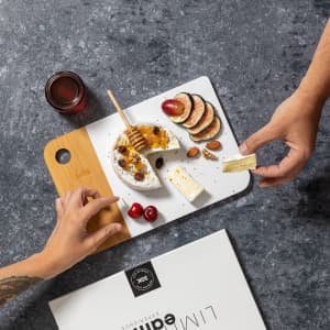 A cheese platter featuring a variety of cheeses, fruits, nuts, and honey, set on a wooden board.