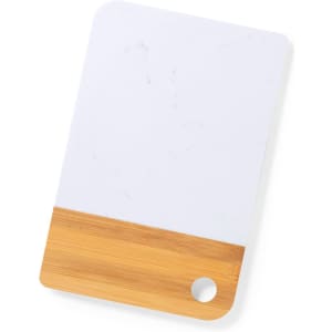 A cutting board featuring a white surface and a bamboo bottom, with a hole for hanging.
