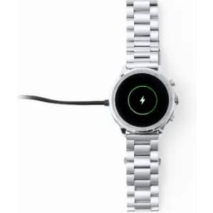 A smartwatch with a silver metal band, showing a charging icon on the screen. The device is connected to a charger.