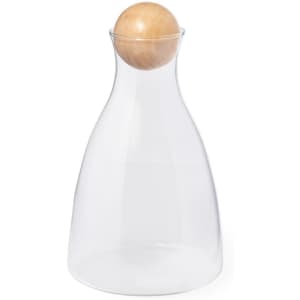 A drink bottle with a clear glass body and a wooden ball stopper at the top.