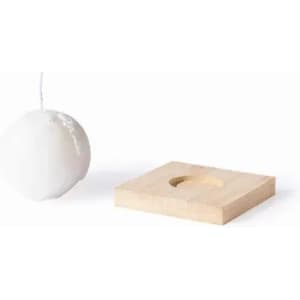 A white candle with a wick next to a square wooden base with a hole in the centre. The base has a natural finish.