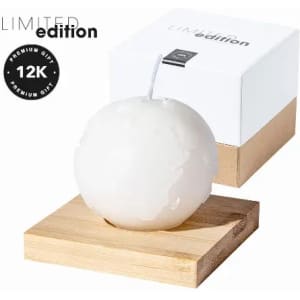 A candle shaped like an apple, featuring a white finish, resting on a wooden base with a gift box.