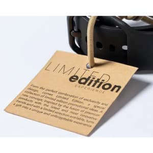 A brown tag with a text description, attached to a black product strap, with a branding logo.