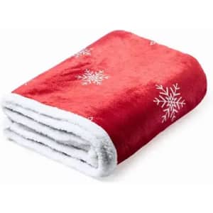 A folded red blanket with white snowflake patterns and a soft, fluffy white underside.