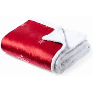 A red blanket featuring white snowflakes and a soft, white fluffy underside. It is neatly folded.