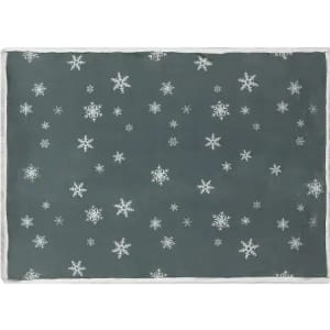 A dark grey mat covered in white snowflake patterns, with a textured edge. It features a festive winter design.