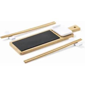 A serving platter made of wood and black slate, accompanied by chopsticks and a small white condiment holder.