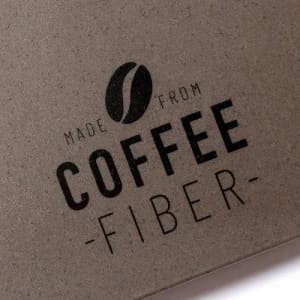 A textured surface featuring the words "made from coffee fiber" in bold lettering. The background is a muted grey colour.