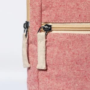A close-up of a red fabric bag with a zipper, featuring a beige zip pull. The bag has a textured appearance.