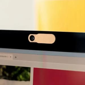 A webcam cover in a wooden finish, placed on the top edge of a computer screen.
