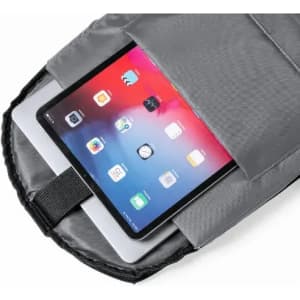A tablet nestled in a grey backpack pocket, featuring a sleek design with a smooth surface. The backpack has a logo.