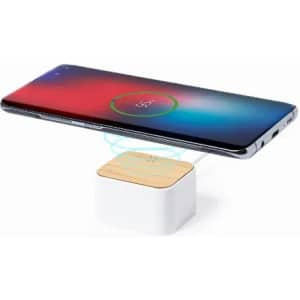 A wireless phone charger with a wooden top and white base, showcasing a smartphone being charged above it.