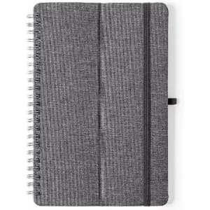 A notebook with a grey fabric cover, spiral binding, and an elastic band closure. It features a simple design.