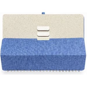 A notebook with a textured blue fabric cover and a speckled beige top, featuring three buttons and spiral binding.
