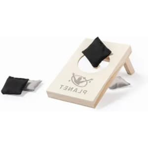 A cornhole game set featuring a wooden board with a hole and two small bags in black and grey. The board has a logo.