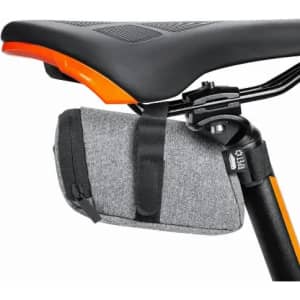 A bike seat bag in grey fabric, secured under a black bike seat, featuring an orange accent. It has a zip closure.