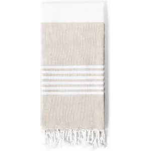 A light beige towel with white stripes and fringe detailing at the ends, featuring a soft texture.