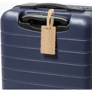 A navy blue suitcase with a textured surface and a wooden luggage tag attached to the handle.