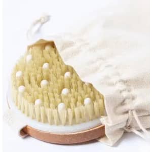 A body brush with natural bristles and a cotton pouch, featuring a round shape and a metallic base.