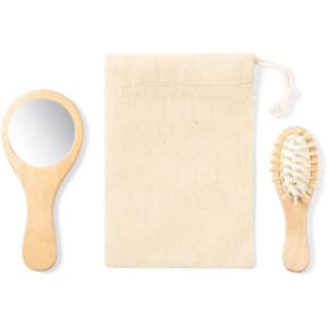 A wooden hairbrush, a handheld mirror, and a natural fabric pouch feature in the image.
