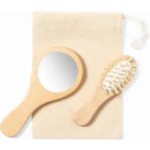 A wooden hand mirror and a matching hairbrush, both placed on a natural fabric pouch.
