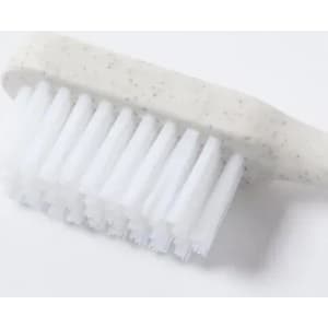 A toothbrush featuring a white handle with speckles and soft white bristles, set against a plain background.