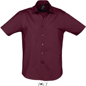 A short sleeve men's shirt in burgundy with a button-up front and a logo on the collar.