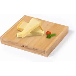 A wooden cheese board with three pieces of cheese and a sprig of mint and a cherry tomato.