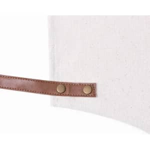 An off-white fabric bag with a brown leather strap and snap buttons.