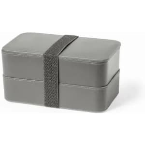 A grey lunch box with two stacked compartments, secured by a fabric strap.