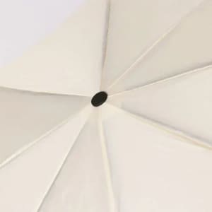 A parasol featuring a cream canopy with a central black knob, showcasing a six-panel design.