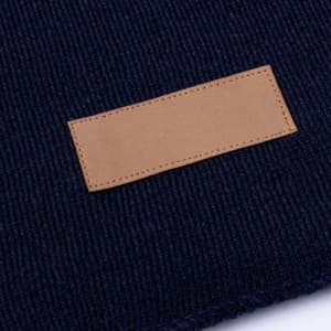A knitted fabric in navy blue featuring a rectangular tan leather patch.
