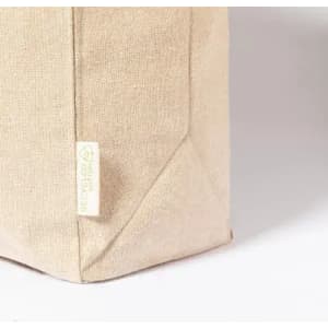 A beige fabric bag with a textured surface and a small logo tag, featuring a simple and minimalist design.