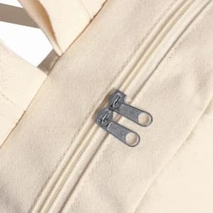 A cream-coloured fabric bag featuring a double zipper closure and sturdy stitching.
