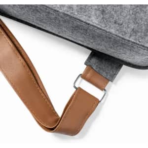 A grey felt bag with a brown leather strap featuring a metal buckle. The strap is attached to the bag's side.