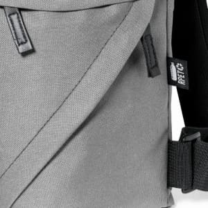 A grey shoulder bag with a textured fabric and adjustable strap, featuring a small brand tag.